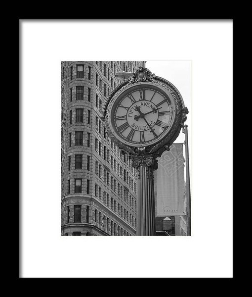 A vintage street clock stands prominently in front of a historic building with a detailed facade.
