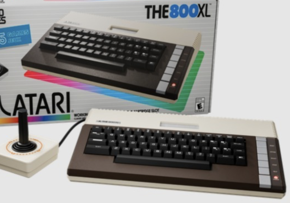 Auto-generated description: An Atari 800XL computer with a joystick controller is shown next to its original packaging.
